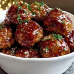 Juicy Slow Cooker Honey Garlic Meatballs glazed with a rich honey garlic sauce and sprinkled with fresh parsley in a white bowl.