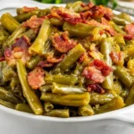 Crock Pot Green Beans with tender slow-cooked green beans and crispy bacon in a white serving dish.