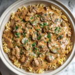 Creamy Crockpot Beef Stroganoff served over egg noodles, topped with parsley and tender mushrooms in a rich sour cream sauce.