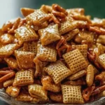 Addicting Toffee Chex Mix piled in a bowl with golden caramel coating and crunchy cereal pieces.