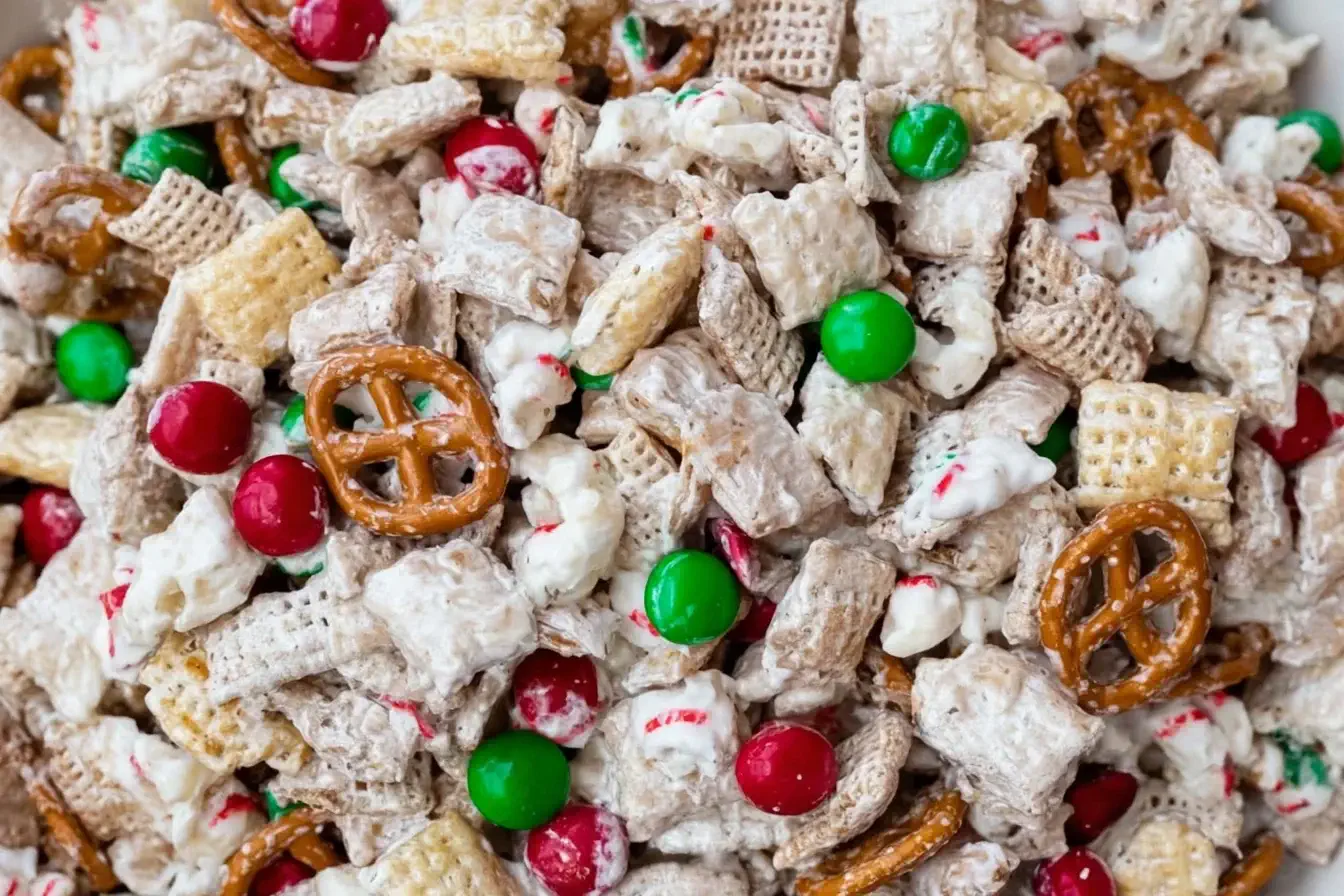 Close-up of Gluten Free Reindeer Chow featuring Chex cereal, pretzels, popcorn, and festive red and green candies coated in white chocolate.
