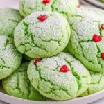 Grinch Cookies topped with powdered sugar and red heart sprinkles arranged on a plate for a festive holiday dessert.