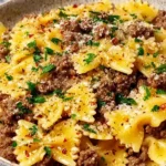 Garlic Butter Bowtie Pasta with Ground Beef topped with Parmesan cheese and fresh parsley in a rustic bowl.