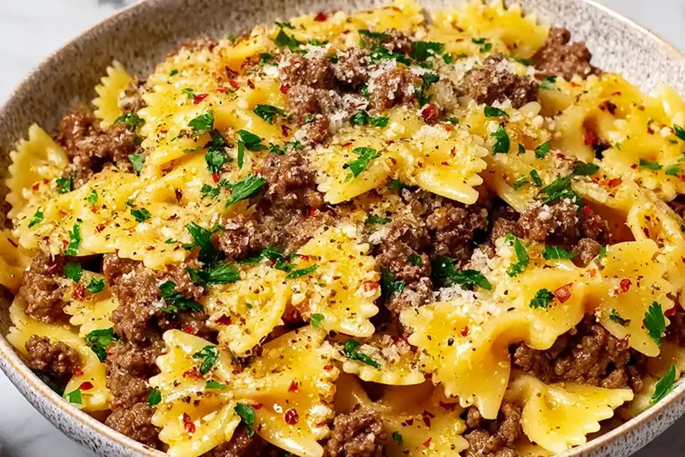 Garlic Butter Bowtie Pasta with Ground Beef topped with Parmesan cheese and fresh parsley in a rustic bowl.