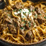Crock Pot French Onion Beef And Noodles served over egg noodles with creamy sauce and fresh parsley on top