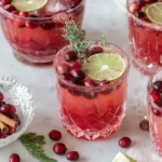 Glasses of Non Alcoholic Christmas Punch garnished with lime slices, cranberries, and rosemary for a festive holiday drink.