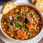 Bowl of hearty Beef Barley Soup with tender beef, carrots, celery, and barley, served with fresh bread.