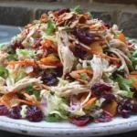 Asian Chicken Cranberry Salad piled high with shredded chicken, dried cranberries, crunchy cabbage, carrots, and toasted almonds