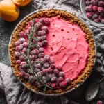 Overhead view of CRANBERRY MEYER LEMON PIE with gingersnap crust surrounded by fresh lemons and cranberries
