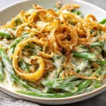 Plate of Campbells Green Bean Casserole with creamy sauce and crispy onion strings.