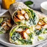 Chicken Caesar Wrap cut in half with crispy chicken, romaine lettuce, and creamy Caesar dressing