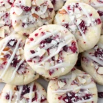 Cranberry Almond Shortbread Cookies with white icing and sliced almonds.