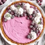 Whole Cranberry Mousse Pie with gingersnap crust topped with whipped cream and sugared cranberries on a white pie plate