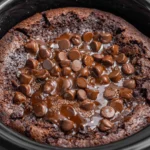 Crockpot Chocolate Lava Cake cooking in a slow cooker with melted chocolate chips on top