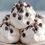 Forgotten Cookies stacked with whipped topping and chocolate shavings