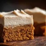 Frosted Gingerbread Brownies with a soft gingerbread base and thick whipped frosting on a wooden surface