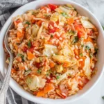 Greek Rice And Cabbage served in a white bowl with tender cabbage, rice, carrots, and tomatoes in a light tomato sauce