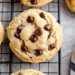Close-up of a homemade chocolate chip cookie cooling on a rack with gooey chocolate chips