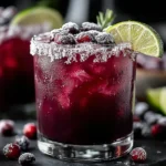 Midnight Frost Christmas Punch with sugared cranberries, lime slices, and a frosty rim.