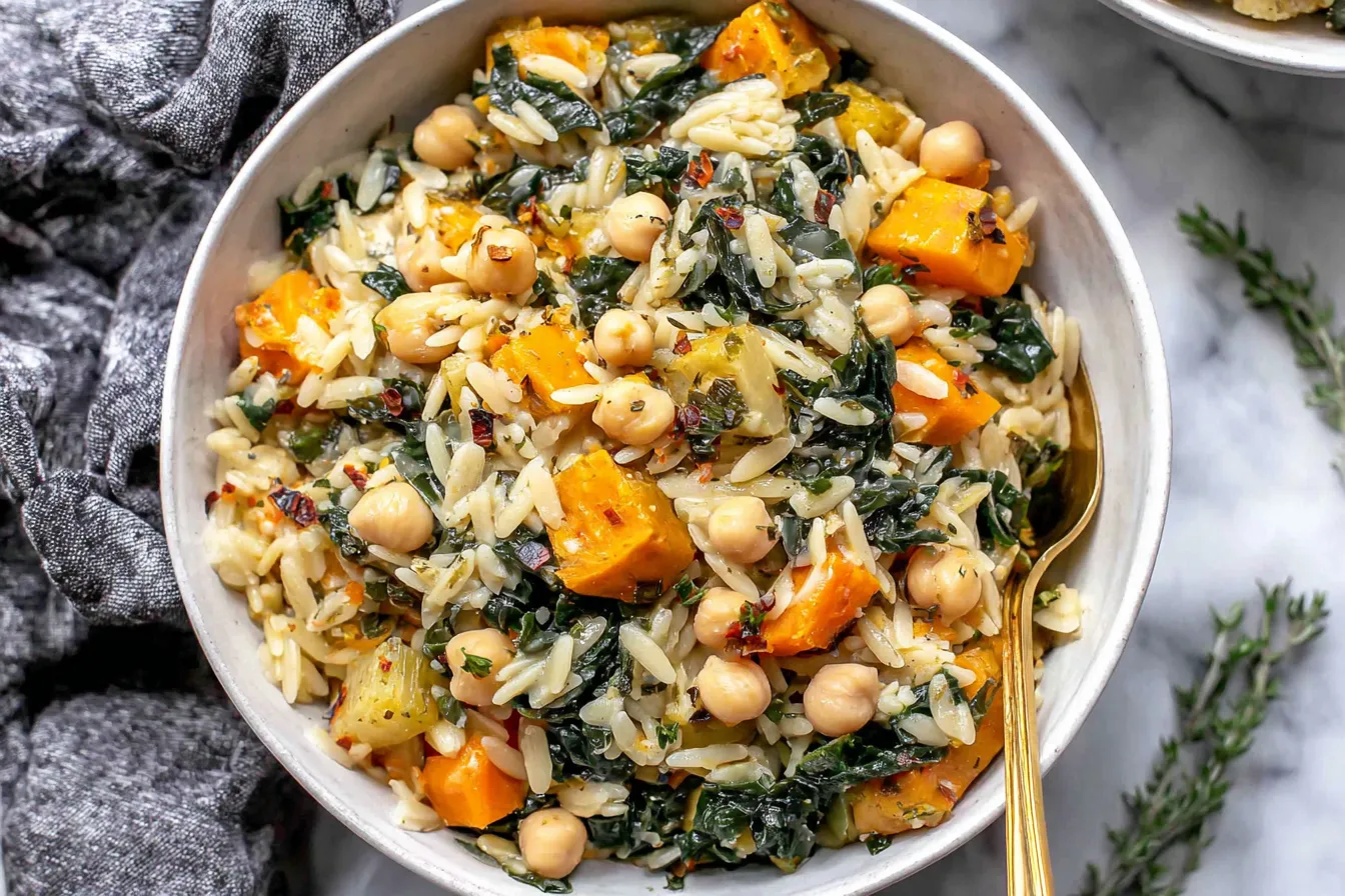 A close-up of One Pot Fall Vegetable Orzos mixed with chickpeas, kale, and soft butternut squash pieces.
