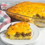 Slice of Overnight Cheesy Sausage and Hashbrown Breakfast Casserole served on a plate with a fork.