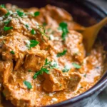 Slow Cooker Thai Peanut Chicken cooking in a crockpot with creamy peanut sauce and fresh herbs