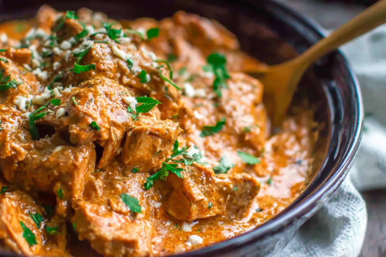 Slow Cooker Thai Peanut Chicken cooking in a crockpot with creamy peanut sauce and fresh herbs