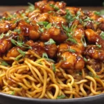 Sticky Garlic Chicken Noodles topped with glazed chicken pieces and sliced green onions.