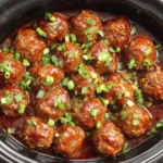 Sweet and Spicy Slow Cooker Meatballs cooking in the crockpot with a thick, flavorful sauce