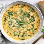 Creamy Tuscan White Bean Soup in a rustic bowl with carrots, kale, and Parmesan.