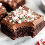Peppermint Brownies with creamy chocolate frosting, topped with crushed peppermint candy and a bite taken out.