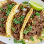 Crock Pot Beef Tacos with tender shredded beef, cilantro, and lime on soft tortillas.
