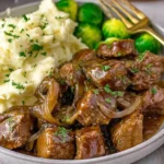 Slow Cooker Steak Bites served with creamy mashed potatoes and tender vegetables, topped with rich gravy and fresh herbs