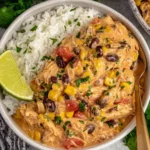 Bowl of creamy Crock Pot Fiesta Chicken served over white rice with black beans, corn, tomatoes, and fresh cilantro