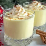 Creamy Homemade Eggnog served in festive glasses topped with whipped cream and cinnamon.