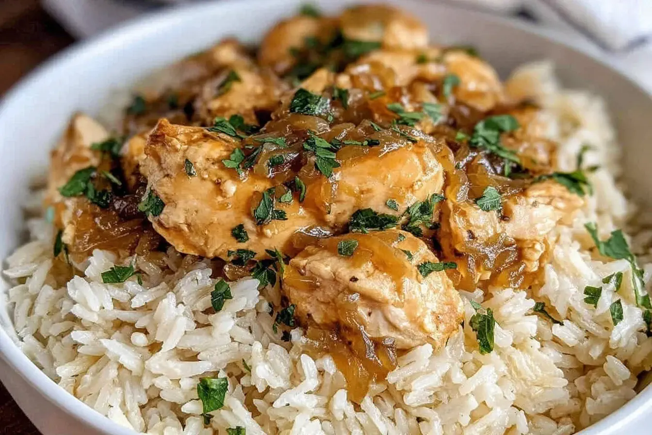 Bowl of Crock Pot No Peek Chicken with Rice featuring tender chicken chunks smothered in rich onion gravy over fluffy white rice.
