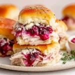 Stacked Turkey Cranberry Sliders overflowing with tender turkey and vibrant cranberry sauce on golden, buttery rolls.