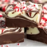 Close-up of rich Peppermint Swirl Fudge with creamy chocolate layers and crushed candy cane pieces on top.