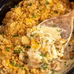 Slow Cooker Chicken Casserole with Ritz Crackers in the crockpot with creamy chicken filling, buttery cracker topping, and a spoon scooping a warm serving.