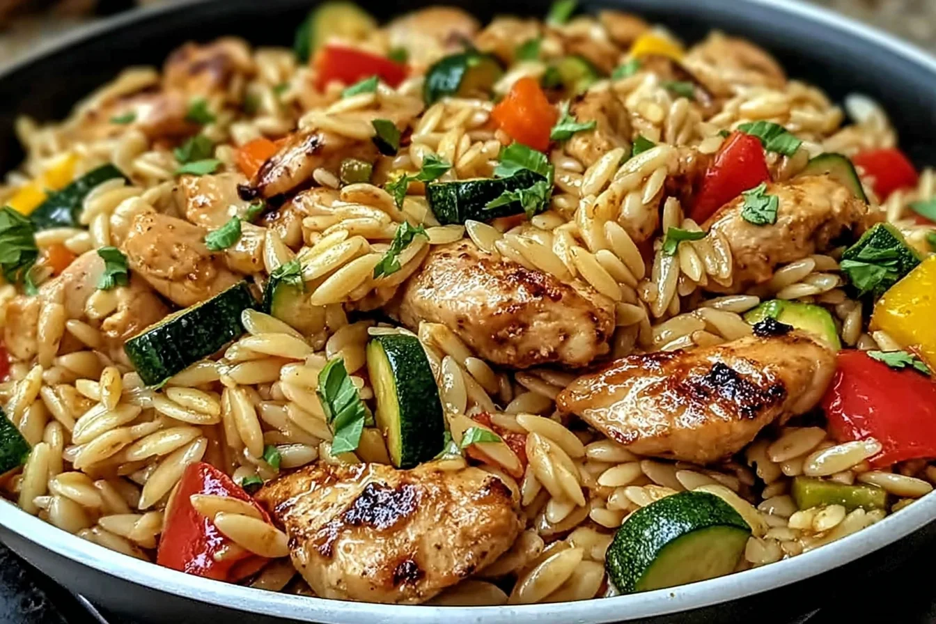 Lemon Chicken and Veggie Orzo Stir Fry in a skillet with juicy chicken, orzo pasta, zucchini, and colorful peppers