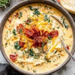 Creamy Slow Cooker Crack Chicken Soup topped with crispy bacon, cheddar cheese, and fresh herbs in a rustic bowl.