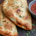 Air Fryer Calzones served with marinara dipping sauce on a wooden board