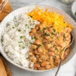 Cheesy Pinto Beans served over fluffy white rice with melted cheddar cheese
