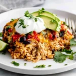 Chicken Burrito Casserole slice served with sour cream, avocado, and cilantro on a white plate