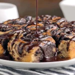 Chocolate Cinnamon Rolls drizzled with rich chocolate glaze on a white plate