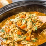 Crockpot Chicken Pot Roast Recipe cooking in a slow cooker with shredded chicken and carrots in gravy