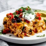 Chicken Burrito Casserole served on a white plate topped with sour cream and fresh cilantro