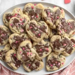 Heart Shaped Chocolate Chip Cookies stacked on a white plate with melted chocolate