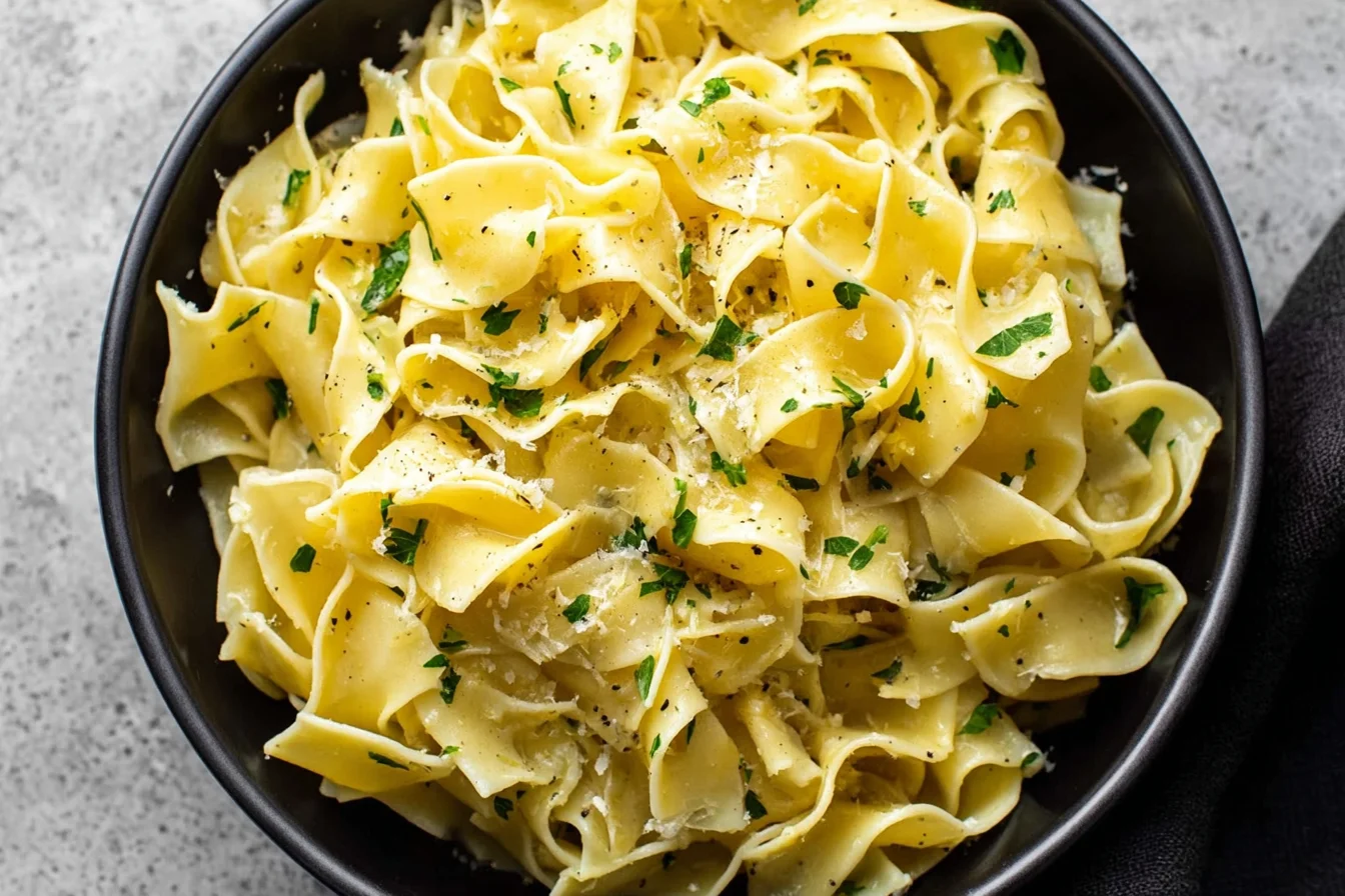 Garlic Butter Noodles in a black bowl, tossed with parmesan, parsley, and cracked black pepper.