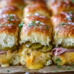 Cuban Inspired Pull-Apart Sliders with ham, Swiss cheese, and pickles on soft rolls, brushed with garlic pickle butter and baked until golden and gooey.